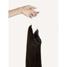 A hand holding a dark brown halo extension by its wire